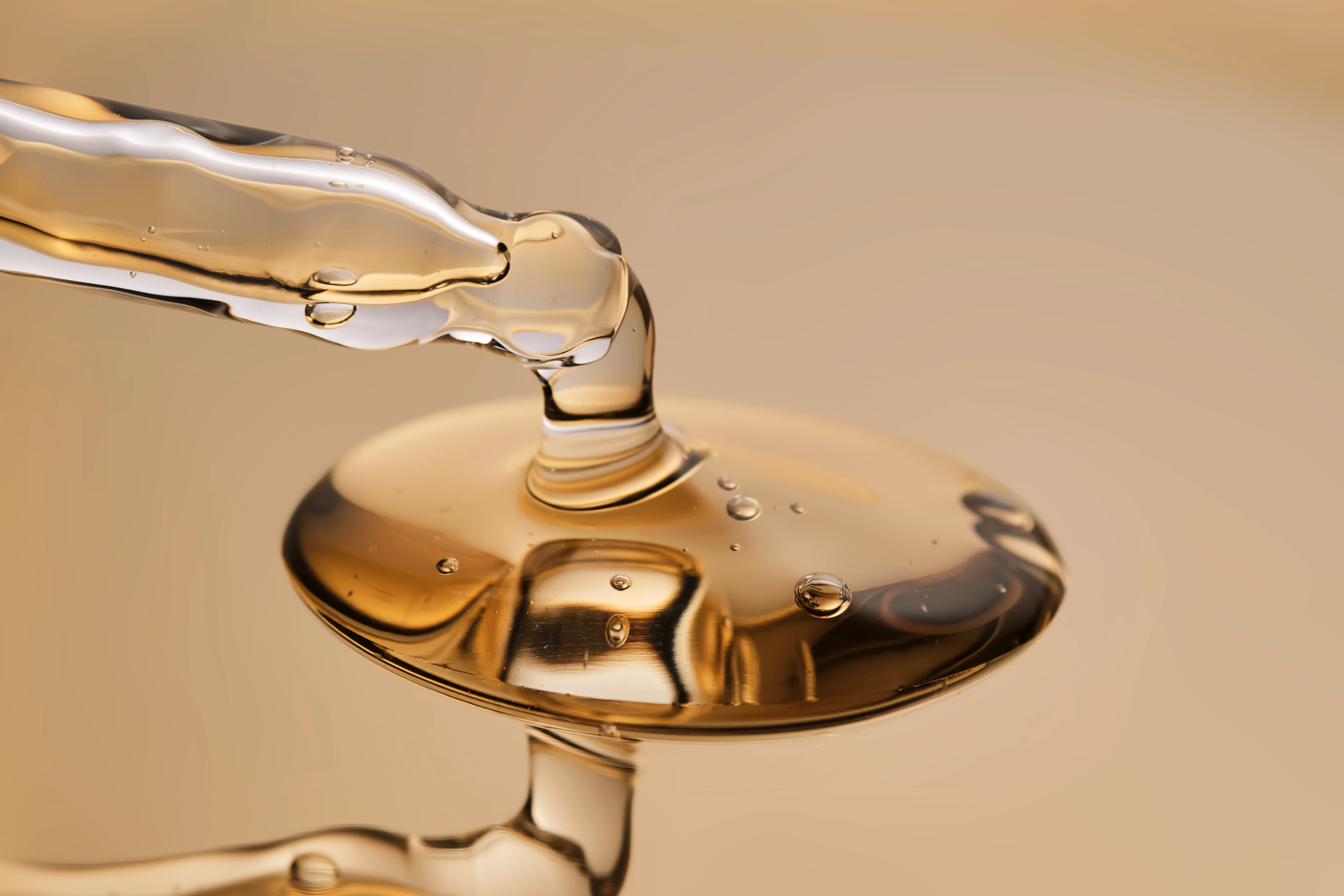 Macro photograph of a pipette suspended above translucent facial serum